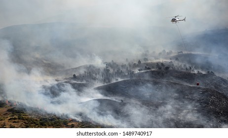 Firefighting Helicopter With Bucket Drop Water On Forest Fire Or Wildfire.