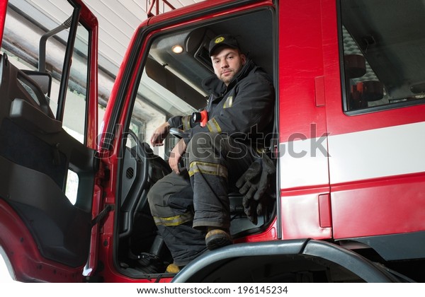 Fireman\
behind steering wheel of a firefighting truck\
