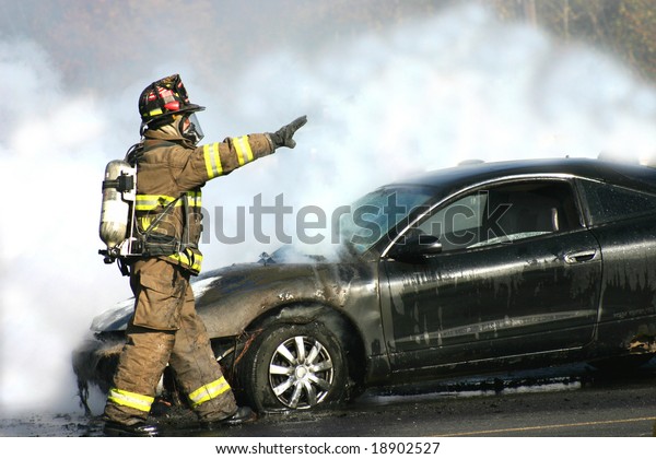 Fireman engulfed in\
smoke from a car fire.