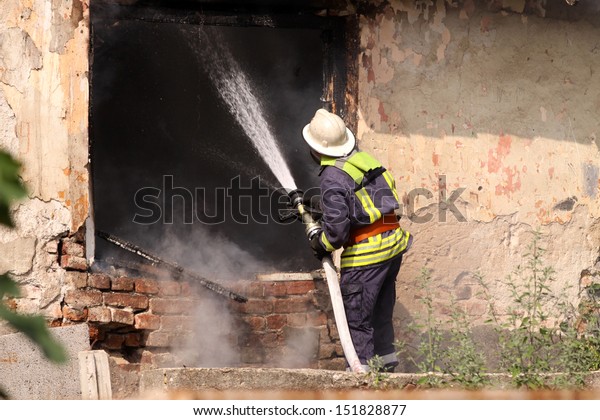 The\
fireman in the form with hose extinguish a\
fire