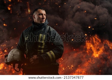 Fireman looking away with hard hat against flame and explosions