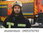 fireman in protective uniform standing near fire engine on station.