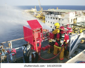 Fireman use fire hose water spray to the sea in part of fire drill or emergency drill training on board for the crew in ship at offshore living quarters, helideck offshore plant form or oil and gas.