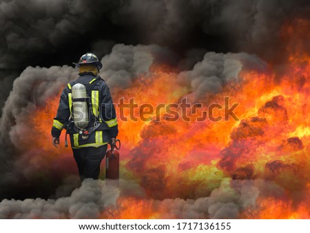 fireman using extinguisher to fighting with fire flame in an emergency situation, under danger situation all firemen wearing fire fighter suit for safety.