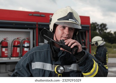 Fireman using walkie talkie at rescue action fire truck and fireman's team in background - Powered by Shutterstock