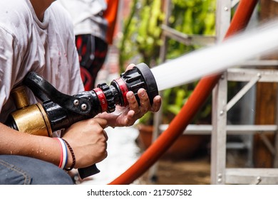 Fireman Using Water Hose To Prevent Fire