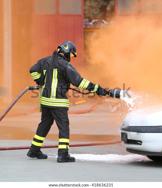 firemen during exercise to extinguish a fire in a\
car with foam