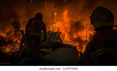 Firemen In Professional Uniform In Front Of The Burning Structure, Fire Of A Falla Sculpture Made Of Paper At Las Fallas Festival In Cullera, Valencia, Spain.