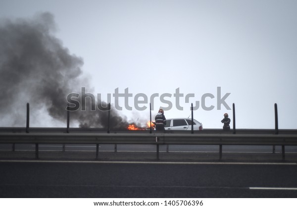 Firemen\
try to extinguish a burning car on a\
highway	