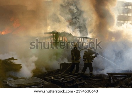 Firemen at work fighting large fire nd smoke