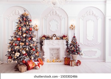Fireplace In Baroque Style Between Christmas Trees Decorated With Red Ornaments. New Year Scene