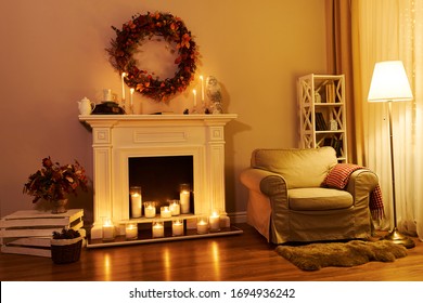 Fireplace, Chair And Floor Decorated Autumn Wreath. Night Windows At The Background. Autumn Interior In A Cozy Hous