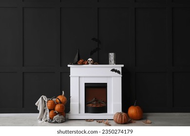 Fireplace decorated for Halloween party near black wall in room