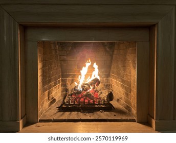fireplace and fire close view as object or background, brick wall. Roaring fire with bright orange flames blazing in a brick hearth for indoor heating, close up view.