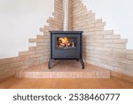 Fireplace inside house living room. Contemporary cosy living room with wood burner stove with burning flame behind a glass door