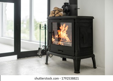 Fireplace at lounge room standing on concrete floor with copy space. Home with modern interior, wooden log on top of fireside and equipment against white wall