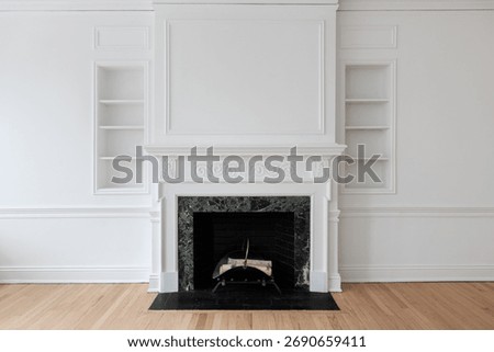 A fireplace with a pattern marble surround, black brick hearth,  with a wainscoting wall, and a white decorative mantel surrounded by shelving.