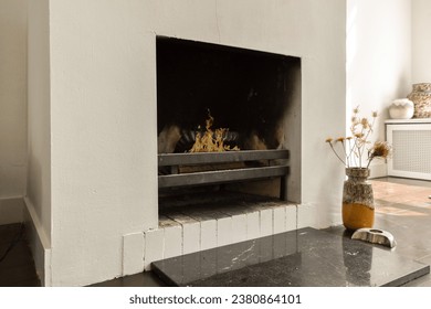a fireplace in a room with white walls and black tiles on the floor, there is an open fire place