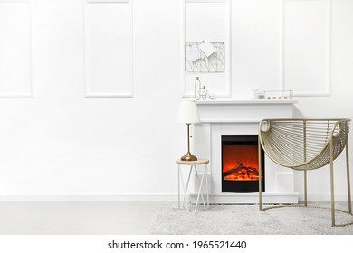 Fireplace with table and armchair in stylish interior of room