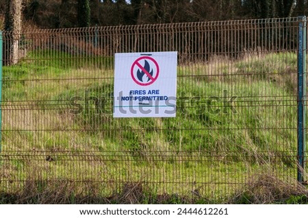 'Fires are not permitted' sign on a chain link fence on a white background