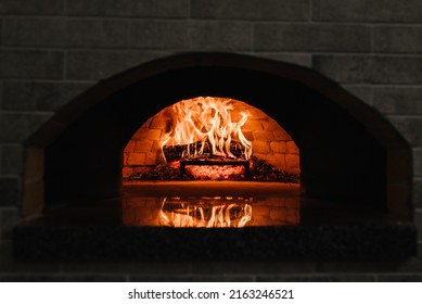 Firewood burning in the oven. Wood-fired oven. Image of a brick pizza oven with fire. A traditional oven for cooking and baking pizza. - Shutterstock ID 2163246521