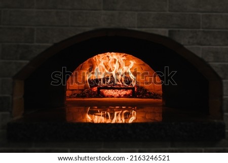 Firewood burning in the oven. Wood-fired oven. Image of a brick pizza oven with fire. A traditional oven for cooking and baking pizza.