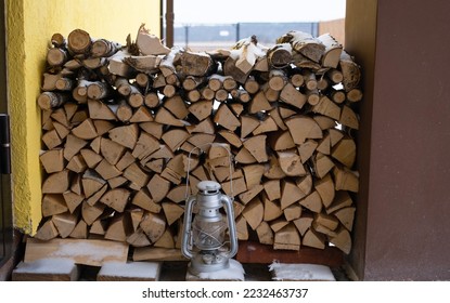 The firewood on the snowy porch of the house is harvested for the winter. Heating of housing with a stove fireplace, saving electricity and gas in a crisis, environmental friendliness. - Shutterstock ID 2232463737