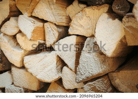 Firewood with snow all over background, close up