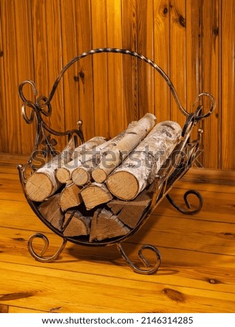 Firewood stack in brass basket by a wooden wall