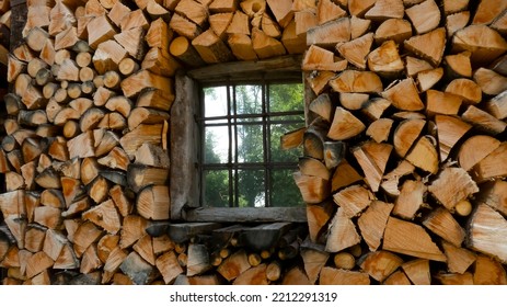 Firewood stack of logs framing a rustic wooden house window