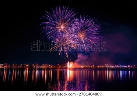 Fireworks explode in purple bursts over a city skyline with vibrant water reflections. Sharp focus captures the grand festive atmosphere. Perfect for holiday and tourism marketing campaigns.