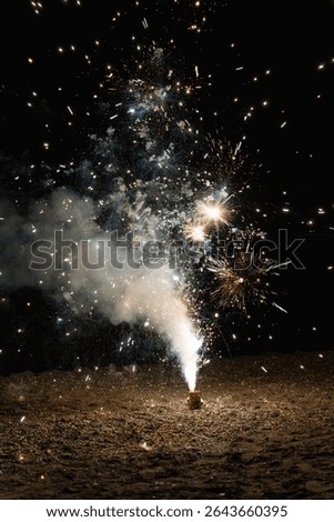 fireworks exploding and shooting sparks and smoke into the night sky above the sandy beach