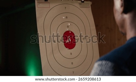 Firing range customer doing shooting activity with pistol, checking if he shot bullseye. Close up of person in shooting gallery learning how to use firearm, analyzing targets shot, camera A