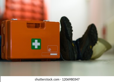 First Aid After An Accident At Work. First Aid Kit And Helmet Near Worker.