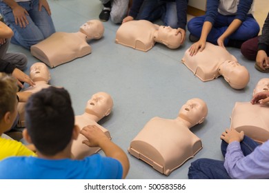 First Aid Cardiopulmonary Resuscitation Course In Primary School. Kids Practicing On Resuscitation Dolls.