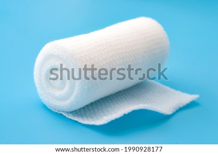 First aid, injury protecting wrapping and wound dressing concept clean cotton gauze bandage isolated on blue background
