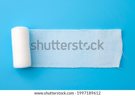 First aid, injury protecting wrapping and wound dressing concept clean cotton gauze bandage isolated on blue background with copy space