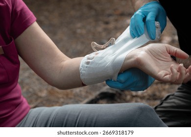 First aid instructor demonstrating proper bandaging technique on simulated arm injury