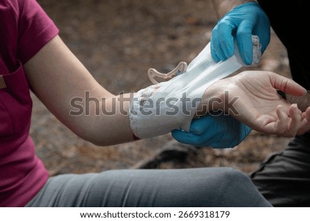 First aid instructor demonstrating proper bandaging technique on simulated arm injury