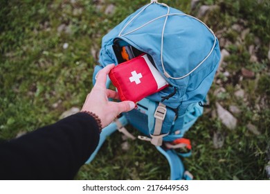 A first aid kit is in a backpack, a hand holds a bag of medicines, an open pocket of a bag, road medicine assistance, camping equipment. High quality photo