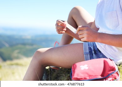 First Aid Kit In A Backpack Tourists. Child Sticking Plaster On Knee.