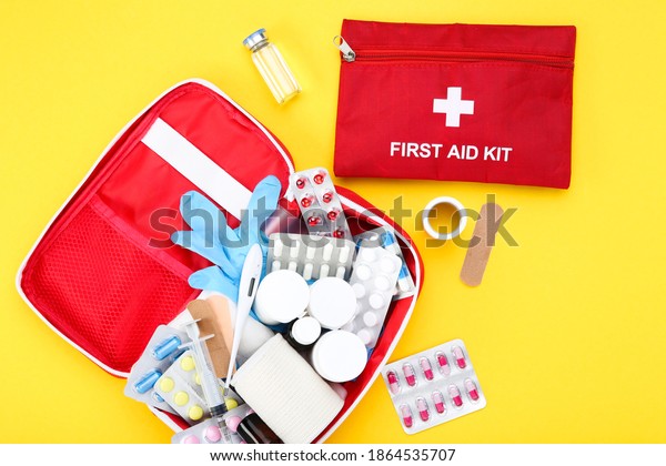 First
aid kit with medical supplies on yellow
background