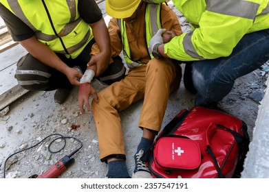 First aid team support to builder worker after hand injury bleeding, accident at work, Using construction power tools unsafe and negligence at the construction site. Safety in work concept.