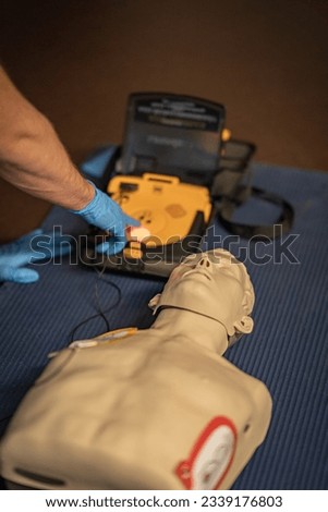 First aid training – The resusitation has started. The instructor ist going to activate the shock. The shock discharge button flashes red. The AED is loaded and the patient is now being shocked.