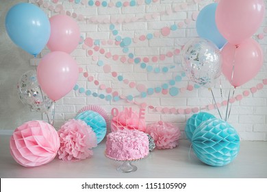 First birthday cake. Smash cake. One year. Pink and blue photo zone with paper garlands, balloons, paper honeycombs and pink cream cake.