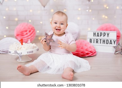 first birthday concept - portrait of cute baby girl holding star and smashed cream cake with birthday decorations