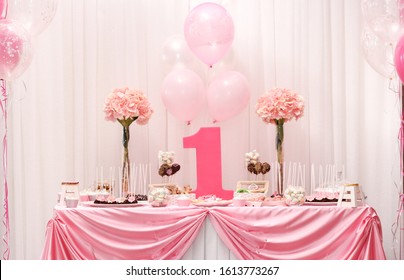 First birthday pink cake. Children's pink cake in the background of balls. First birthday girl. Copy space. Candy bar. The first cake.