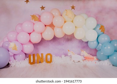 First birthday smashcake photo session with a rainbow of balloons and unicorns in a photo studio