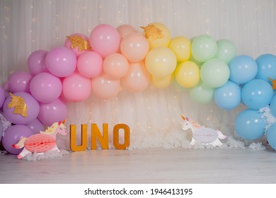 First birthday smashcake photo session with a rainbow of balloons and unicorns in a photo studio