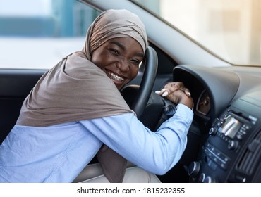 First Car. Happy Black Muslim Woman In Hijab Hugging Steering Wheel, Bought New Vehicle, Sitting In Auto In Dealership Center Showroom, Smiling At Camera, Closeup Shot With Copy Space